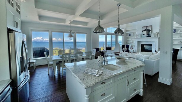 A spacious kitchen with a large island, white cabinetry, and a view of the ocean. - Oceanfront Luxury Retreat at Sandy Point Shores. (Ferndale)