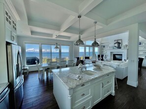 A spacious kitchen with a large island, white cabinetry, and a view of the ocean. - Oceanfront Luxury Retreat at Sandy Point Shores. (Ferndale)