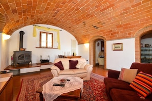 A cozy living room with a brick ceiling, a sofa, a red couch, a wooden coffee table, and a fireplace.