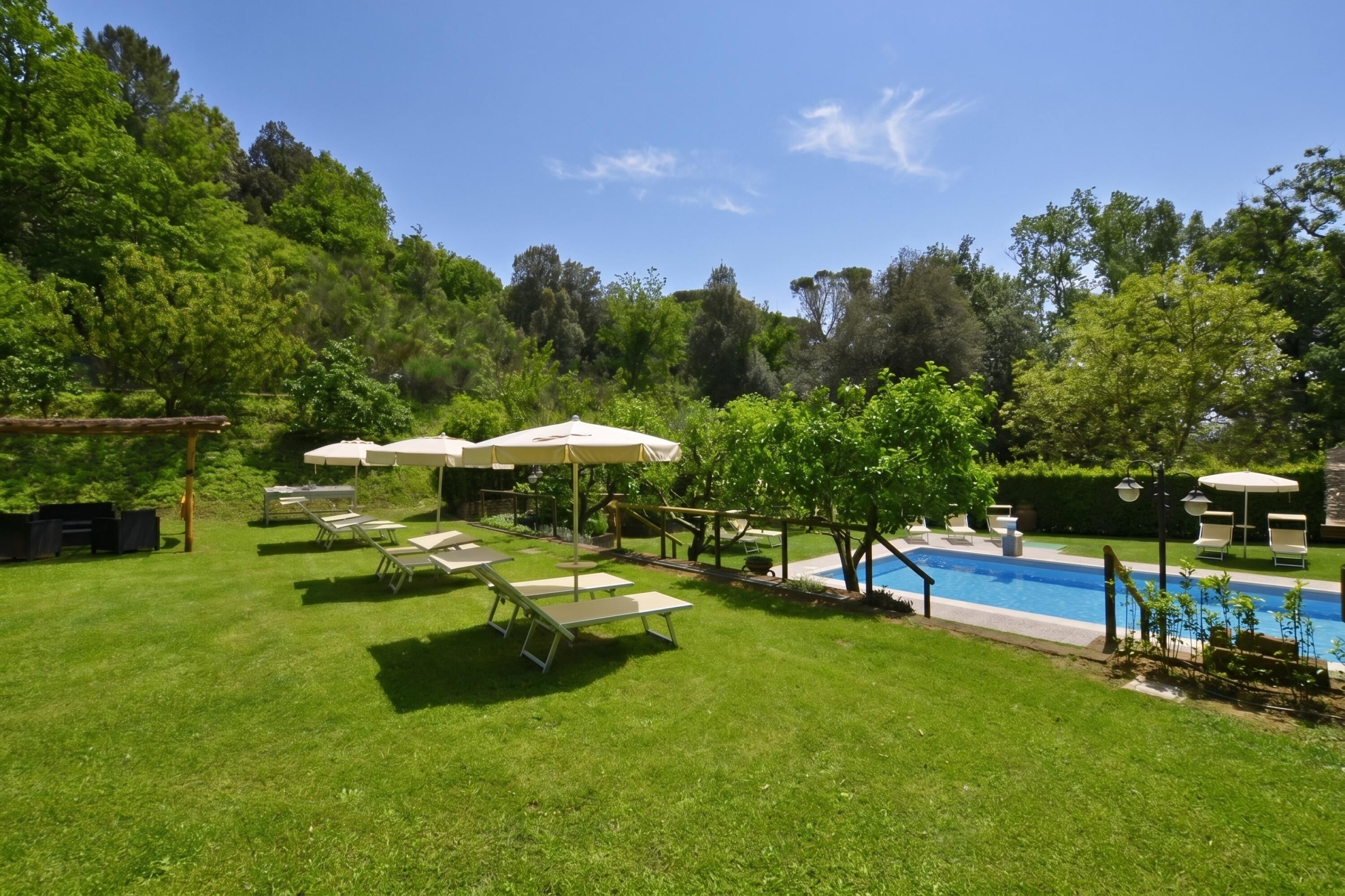 Un patio trasero con piscina, sillas de descanso y sombrillas.