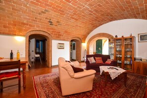 Ein Wohnzimmer mit Backstein Decke, einer Couch, einem Tisch und einem Schrank.