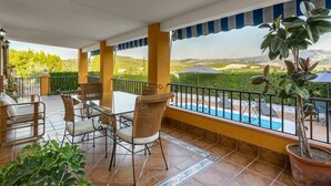A covered patio with a pool, outdoor furniture, and a view of the countryside.