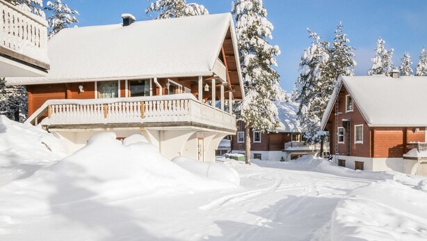 A snow-covered building with a balcony and a wooden exterior.