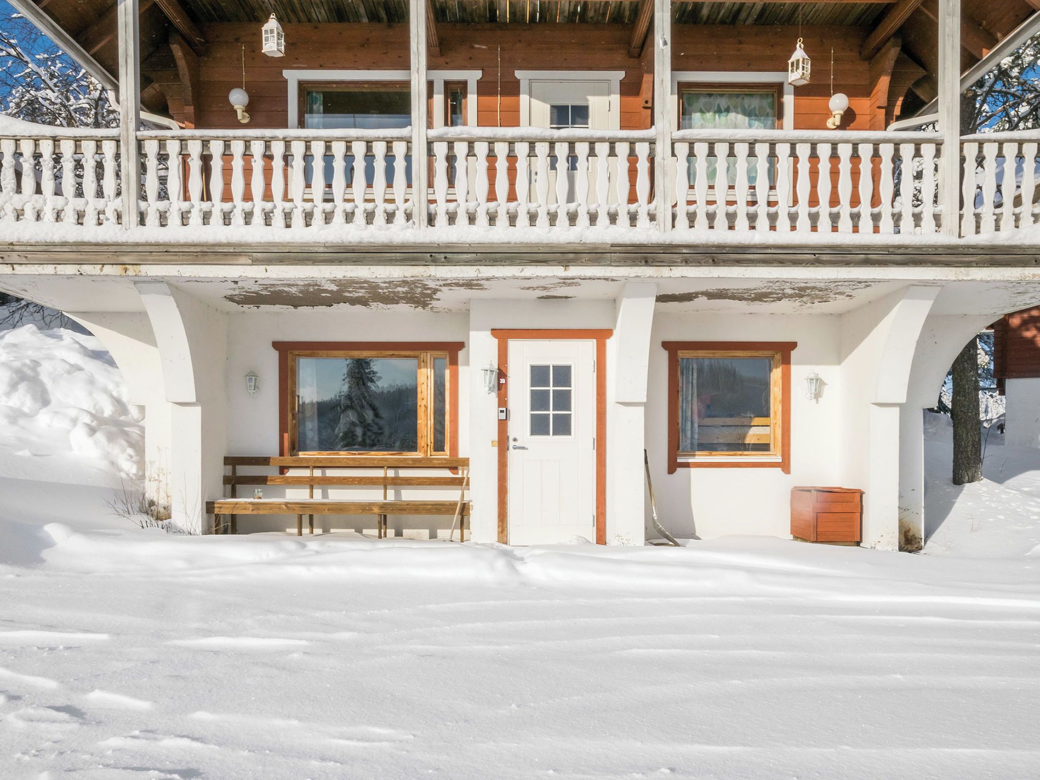 Un chalet in legno con un balcone, una panchina e una porta.