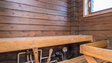 A wooden cabin interior with a bench, a window, and visible plumbing.