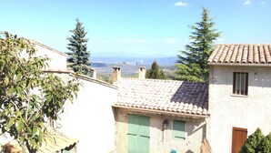 Ein traditionelles Gebäude mit einem Ziegeldach, einem kleinen Innenhof und Blick auf ferne Berge.
