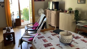 Ein gemütliches Wohnzimmer mit einer Couch, einem Esstisch und einem Fernseher auf einer Holzkommode.