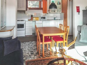 Eine kompakte Küche mit Essbereich, inklusive Tisch und Stühlen, einer Couch und einem gemusterten Teppich.