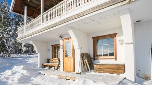 Un edificio cubierto de nieve con un balcón y una puerta de madera, además de una ventana.