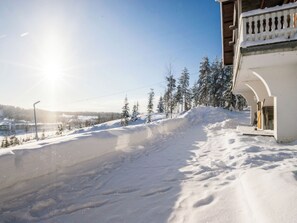 En snötäckt sluttning med en byggnad på höger sida, och byggnaden har en balkong med räcken.