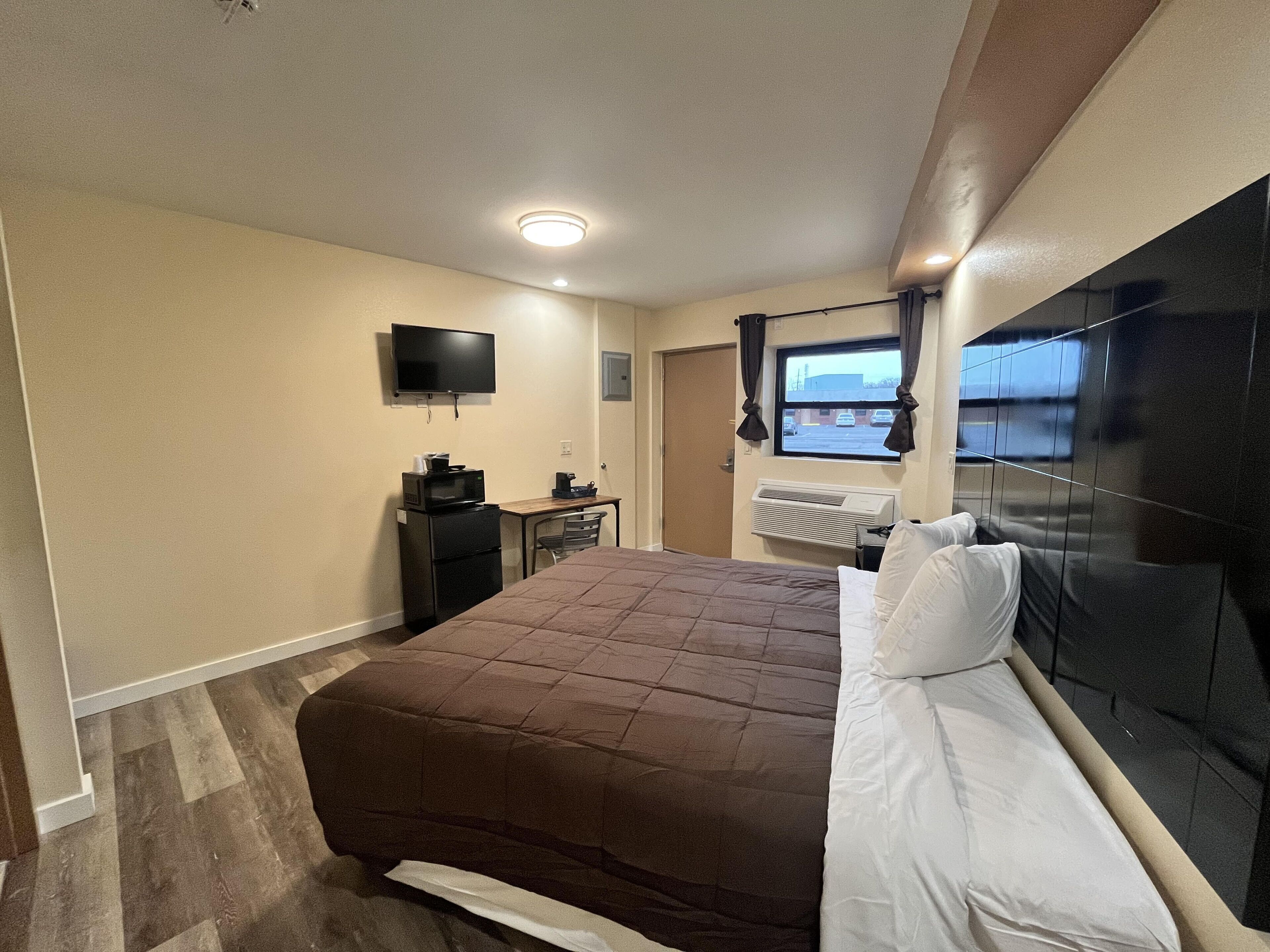 Une chambre d’hôtel équipée d’un lit, d’un bureau avec un ordinateur, d’une télévision et d’un climatiseur.