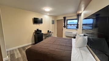 Une chambre d’hôtel équipée d’un lit, d’un bureau avec un ordinateur, d’une télévision et d’un climatiseur.