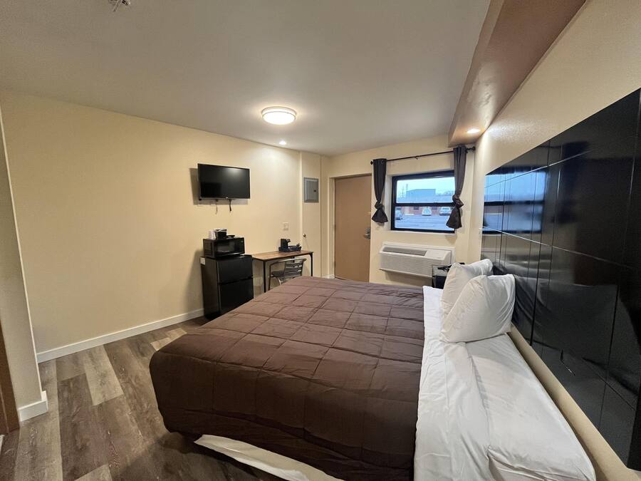 Une chambre d’hôtel équipée d’un lit, d’un bureau avec un ordinateur, d’une télévision et d’un climatiseur.