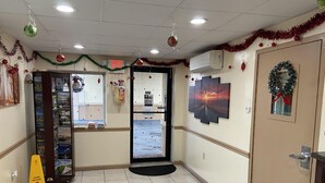 A hotel lobby with a wet floor sign, a reception desk, a wall-mounted exit sign, and a door with a wreath decoration.