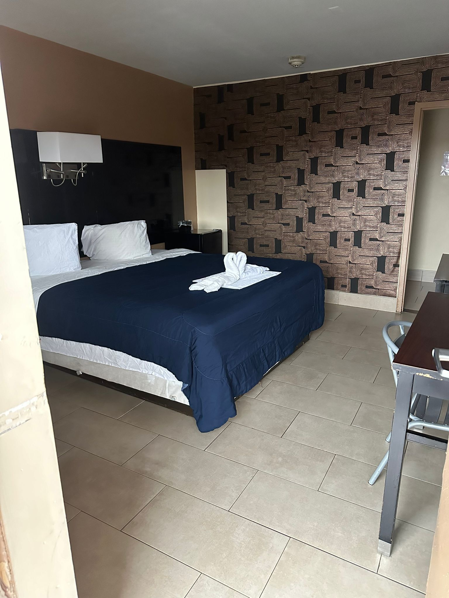 Une chambre d’hôtel avec un lit, un bureau et un mur décoré de motifs.