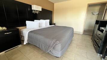 A hotel room with a large bed, a black headboard, a bedside table with a telephone, and a wardrobe.