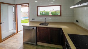 A modern kitchen with a dishwasher, a sink, and a window overlooking a garden. - Chalet Conil Ramirez with private pool (Conil de la Frontera)