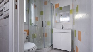 Ein modernes Badezimmer mit einer gläsernen Duschkabine, einer Toilette und einem Waschbecken mit Spiegel darüber.