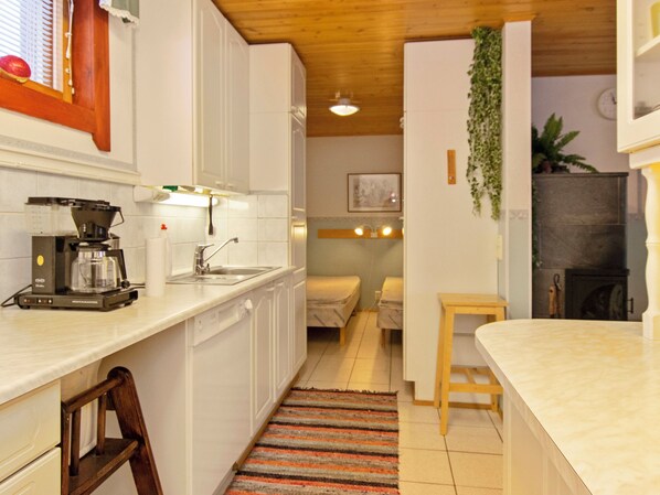 Cocina compacta con cafetera, lavamanos y un pequeño comedor.