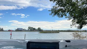 A boat with a Canadian flag, calm water, and a distant shoreline with buildings and trees. - Waterfront property 25 min from Waterton (Hill Spring)