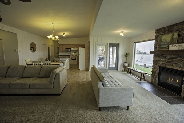 A spacious living room with a fireplace, a sofa, a bench, and a view of the outdoors.