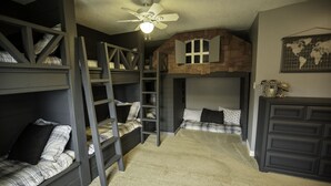 A bunk bed room with a loft bed, a ladder, a ceiling fan, and a world map on the wall. - Waterfront property 25 min from Waterton (Hill Spring)