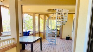 A wooden deck with a table and chairs, a spiral staircase, and a view of the outdoors. - Spend some time on Puako Beach. (Waimea)