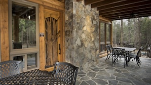 Une terrasse couverte avec un sol en pierre, des poutres en bois et du mobilier en métal.