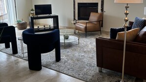 Una sala de estar con chimenea, televisor, ventilador de techo y sofá.