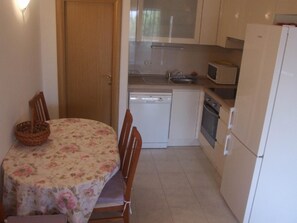 Functional kitchen area with dining table for four, featuring a dishwasher, microwave, and oven.