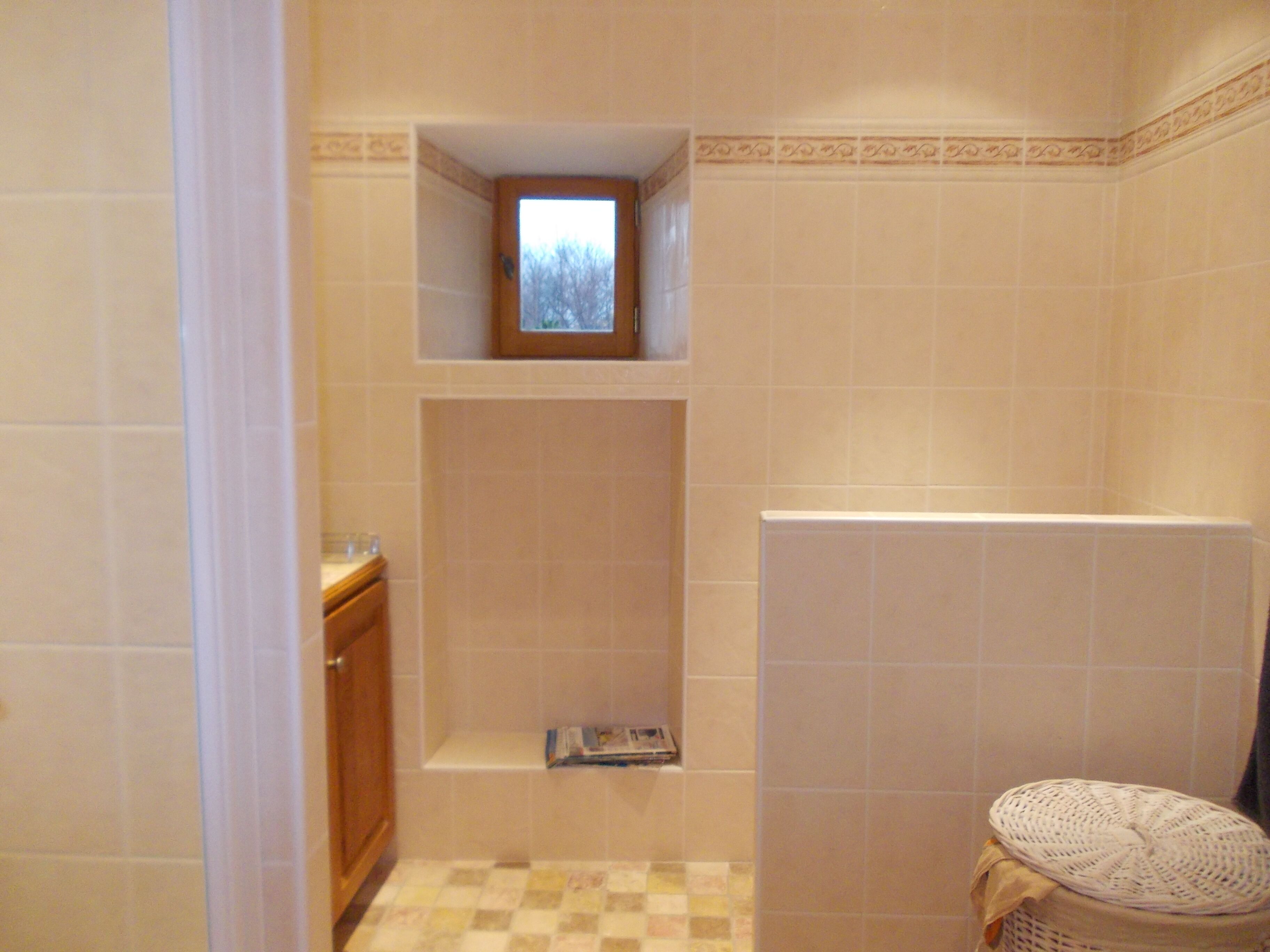 Un baño con ducha, una ventana pequeña y piso de baldosas.
