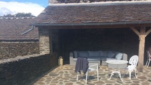 Une terrasse en pierre avec une piscine, un espace salon extérieur et un mur en pierre.