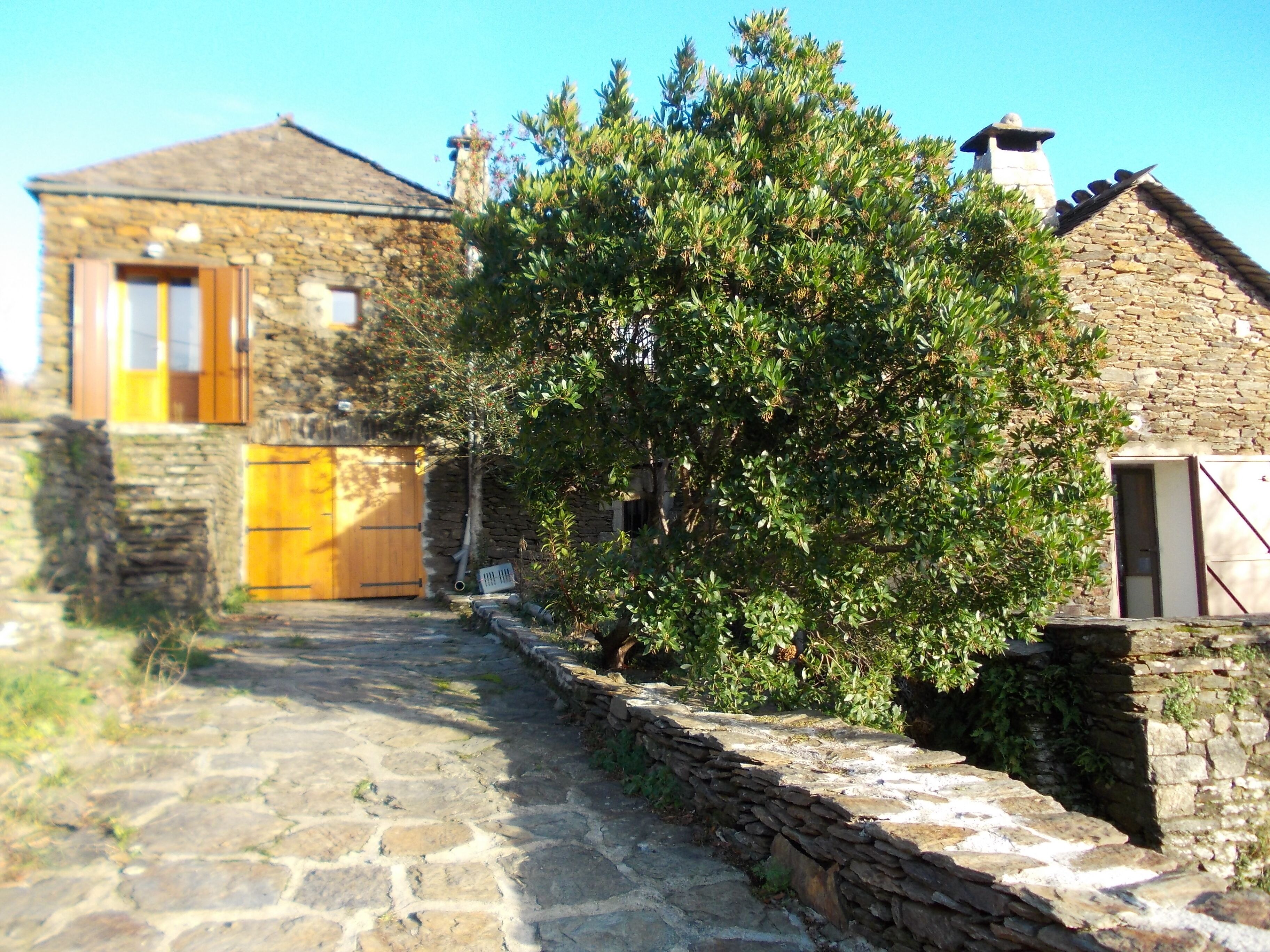 A stone building with a wooden door and a stone wall.