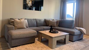 A modern living room with a grey sectional sofa, a wooden coffee table, and a large painting of a leopard. - Notodden Sentrum Apartment NO 6 (Notodden)