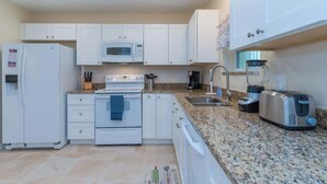 Una cocina moderna con armarios blancos, un microondas, un horno, un fregadero y un tostador.