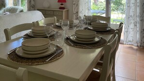 A dining area with a table set for four, a bed with a nightstand, a lamp, and a painting on the wall. - Luxury villa with garden in a secure residence - beach at 700m (Roquebrune-sur-Argens)