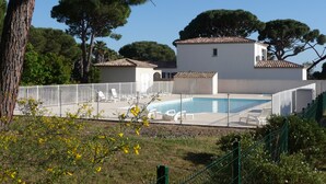 A building with a swimming pool, surrounded by a fence, and trees in the background. - Luxury villa with garden in a secure residence - beach at 700m (Roquebrune-sur-Argens)