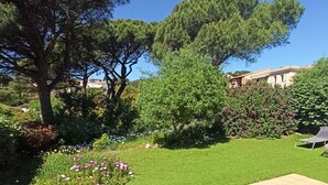 A well-maintained garden with a variety of plants and flowers, a lawn, and a patio area. - Luxury villa with garden in a secure residence - beach at 700m (Roquebrune-sur-Argens)