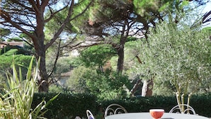 A round metal table with chairs, surrounded by a well-maintained lawn and trees. - Luxury villa with garden in a secure residence - beach at 700m (Roquebrune-sur-Argens)