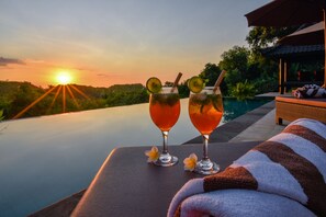 Two cocktails on a table with a sunset view.