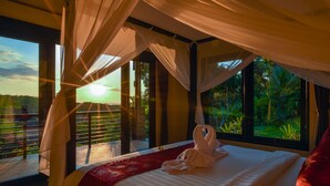 Ein Schlafzimmer mit einem großen Bett, einem Baldachin und Blick auf Grün.