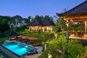 A resort with a swimming pool, outdoor seating, and a covered area with a view of the pool.