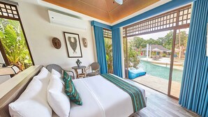 A hotel room with a bed, a small table, chairs, and a view of a pool and outdoor area. - TAG RESORT  (Coron)