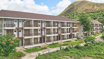 A multi-story hotel with balconies, a hillside backdrop, and a landscaped garden.