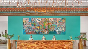 A reception desk with a colorful abstract mural, wooden paneling, and a teal wall. - TAG RESORT  (Coron)