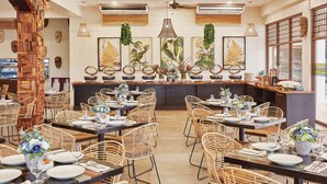 A restaurant with wicker chairs, round tables, and a central bar area. - TAG RESORT  (Coron)