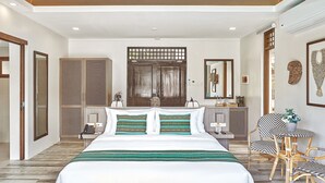 A modern hotel room with a large bed, wooden flooring, a desk with a chair, and a large mirror. - TAG RESORT  (Coron)