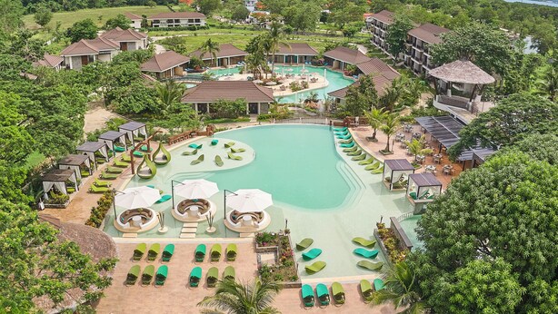 A resort with a large central pool, multiple villas, and lush greenery. - TAG RESORT  (Coron)