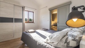 Een slaapkamer met een bed, een raam, een lamp en een kledingkast.