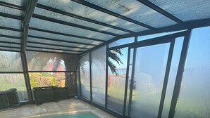 Ein überdachter Innenpool mit Glasfassade, klarem Wasser und Blick ins Freie.